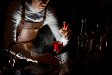 Bartender spraying on the red alcoholic cocktail