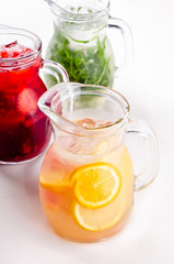 Cold and refreshing citrus cocktail with grapefruit and orange, strawberry, apple, lemon and herbs. Water for detox or dieting in glass jug on white background, copy space. Homemade drink.