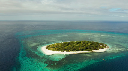 Small tropical island on an atoll with beautiful sandy beach surrounded by coral reef from above....