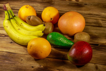 Assortment of tropical fruits on wooden table. Still life with bananas, mango, oranges, avocado, grapefruit and kiwi fruits