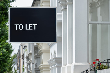 Estate agent 'TO LET' sign on street of urban houses