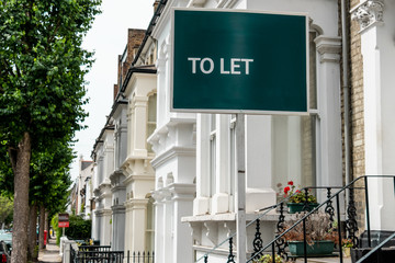 Estate agent 'TO LET' sign on street of urban houses