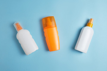 Sun cream, cream, towel, sunscreen bottle, sun cream, lotion bottle, sunglasses seashells on a blue background. Sun protection. Beach flat lay accessories. Summer travel holiday concept.