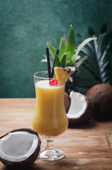 Tropical caribbean cocktail Pina Colada in a glasses on wooden  table with coconut and pineapple.