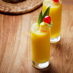 Tropical  cocktail pineapple  in a glasses, garnished with  cherries maraschino on wooden  table .