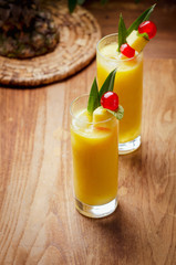 Tropical  cocktail pineapple  in a glasses, garnished with  cherries maraschino on wooden  table .