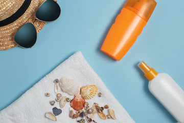 Sun cream, sun hat, cream, sunscreen bottle, sun cream, lotion bottle, sunglasses seashells on a blue background. Sun protection. Beach flat lay accessories. Summer travel holiday concept