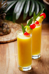 Tropical  cocktail pineapple  in a glasses, garnished with  cherries maraschino on wooden  table .