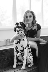 beautiful tall girl in black dress with dog Dalmatian in studio