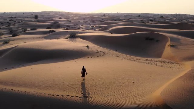 Woman walking in the desert at sunset aerial
