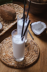 Coconut milk  in glasses with nuts on wooden board.