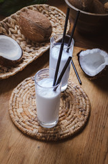 Coconut milk  in glasses with nuts on wooden board.
