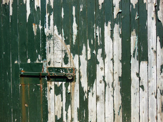 Minimal view of a weathred wooden door with peeling paint;