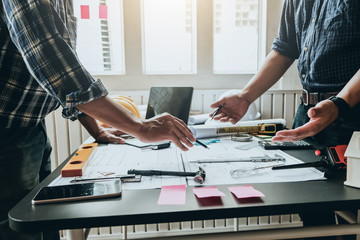 Engineer and contractor planning projects together at desk with blueprints.