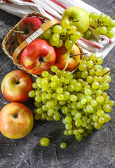 Naklejka na ściany i meble Harvest of apples and grapes on a stone background. Autumn harvest.