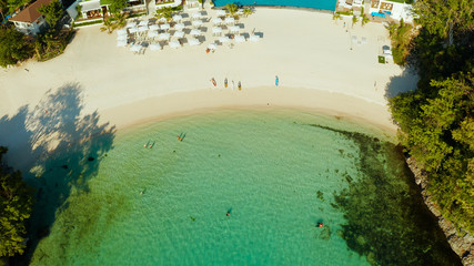 Cove with white beach in blue lagoon with turquoise waters, aerial view. Seascape with beach on tropical island. Summer and travel vacation concept.