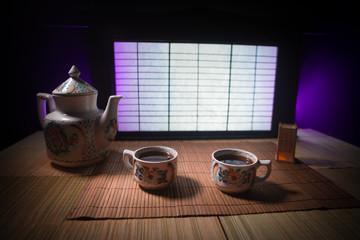 Tea concept. Japanese tea ceremony culture east beverage. Teapot and cups on table with bamboo leaves on sunset