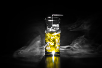 Cocktail glass splashing on dark toned smoky background or colorful cocktail in glass. Party club entertainment. Mixed light.