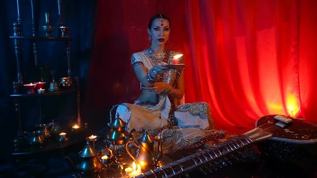 Beautiful young indian woman in traditional Sari clothing and Oriental Jewelry with candle