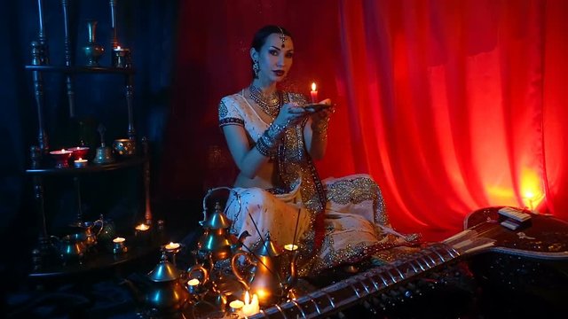 Beautiful young indian woman in traditional Sari clothing and Oriental Jewelry with candle
