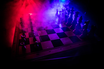 Chess board game concept of business ideas and competition. Chess figures on a dark background with smoke and fog.