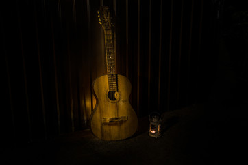 Fototapeta na wymiar An wooden acoustic guitar is against a grunge textured wall. The room is dark with a spotlight for your copyspace.