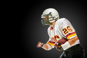 American football player posing with ball on black background. Super Bowl concept. Concept American football, portrait American, Motivator. Black white background, copy space.