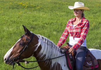 Obraz premium Cowgirl on horse in grass