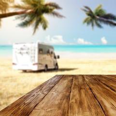 Obraz premium Table background with wooden board in the beautiful ocean and beach view. Palm leaves and clear sunny sky. Free space on a wooden table for an advertising product.