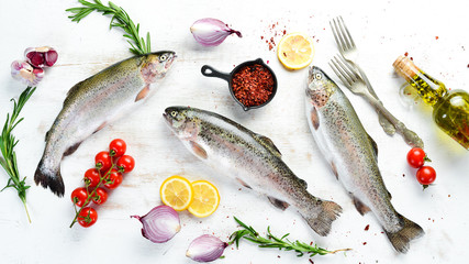Raw fish with vegetables on a white wooden background. Fish trout. Top view. Free space for your...