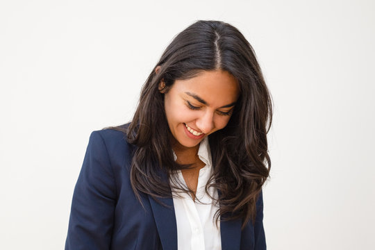 Happy Young Woman Looking Down. Portrait Of Beautiful Smiling Brunette Businesswoman Isolated On Grey Background. Emotion Concept