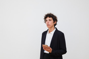 Serious businesswoman holding smartphone. Professional middle aged businesswoman in formal wear using cell phone and looking away isolated on grey background. Technology concept