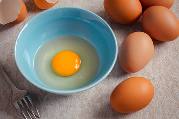 Raw broken egg with yolk in bowl .