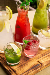 Summer soft drinks, a set of lemonades. Lemonades in jugs on the table, the ingredients of which they are made are arranged around.