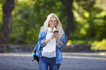 Front view of young excited female student receiving good news on line in a mobile phone in an...