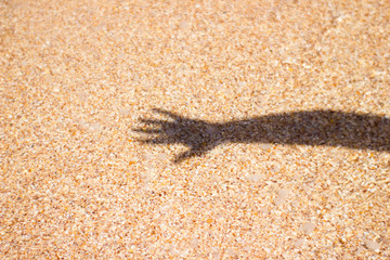 Sea water shadow from girl's hand on sand background texture