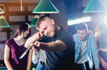 Fototapeta premium Young man playing in billiard. Posing near the table with a cue in his hands