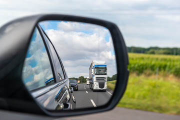 Fototapeta na wymiar Asphalt road with truck reflected in car mirror.