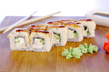 Rolls with fish and sesame seed on top served in wooden board with wasabi, ginger and soy sause