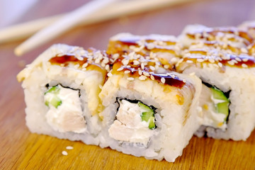 Rolls with fish and sesame seed on top served in wooden board