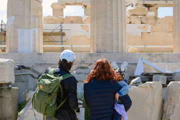 A man and a woman with a little girl in their arms consider the ruins of the temple. Ancient Greek...