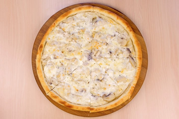 Pizza with mushrooms champignons and cheese on wooden board on the table. Close-up top view