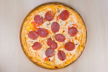Salami pizza on wooden board on the table. Close-up top view