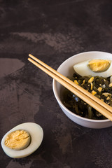 Far Eastern salad - sea kale with egg in a white cup.