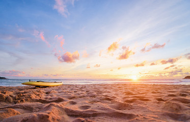 Beautiful landscape. Sunset on the sea beach with lifeguard surf board on sand.