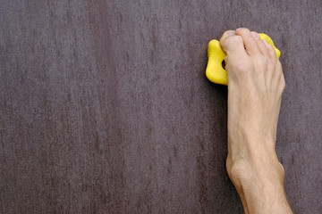 human right barefoot like a hand holds on yellow climbing hold on artificial climbing wall, concept of fun and joy sport, close-up copy space