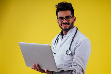 Portrait of indian male doctor checking medicine in yellow studio background