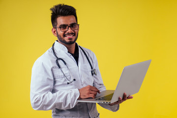 Portrait of indian male doctor checking medicine in yellow studio background