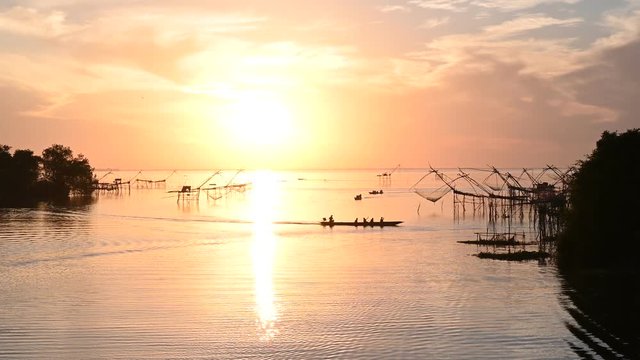 View Silhouette Wooden boat fishermen net fishing in the lake at sunrise time.Amazing at Pak Pra Village Phatthalung, Thailand.4K footage