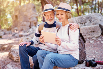 Travel and technology. Senior traveling family couple using tablet computer at ancient sightseeing.